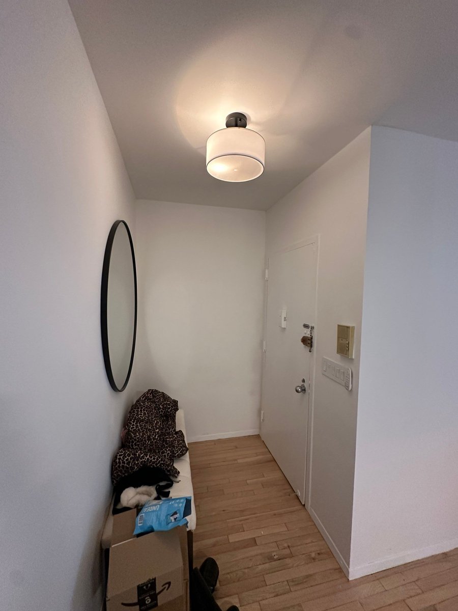 apartment renovation entryway with round black framed mirror drum pendant light hardwood floors and front door in manhattan valley ny by modo renovations
