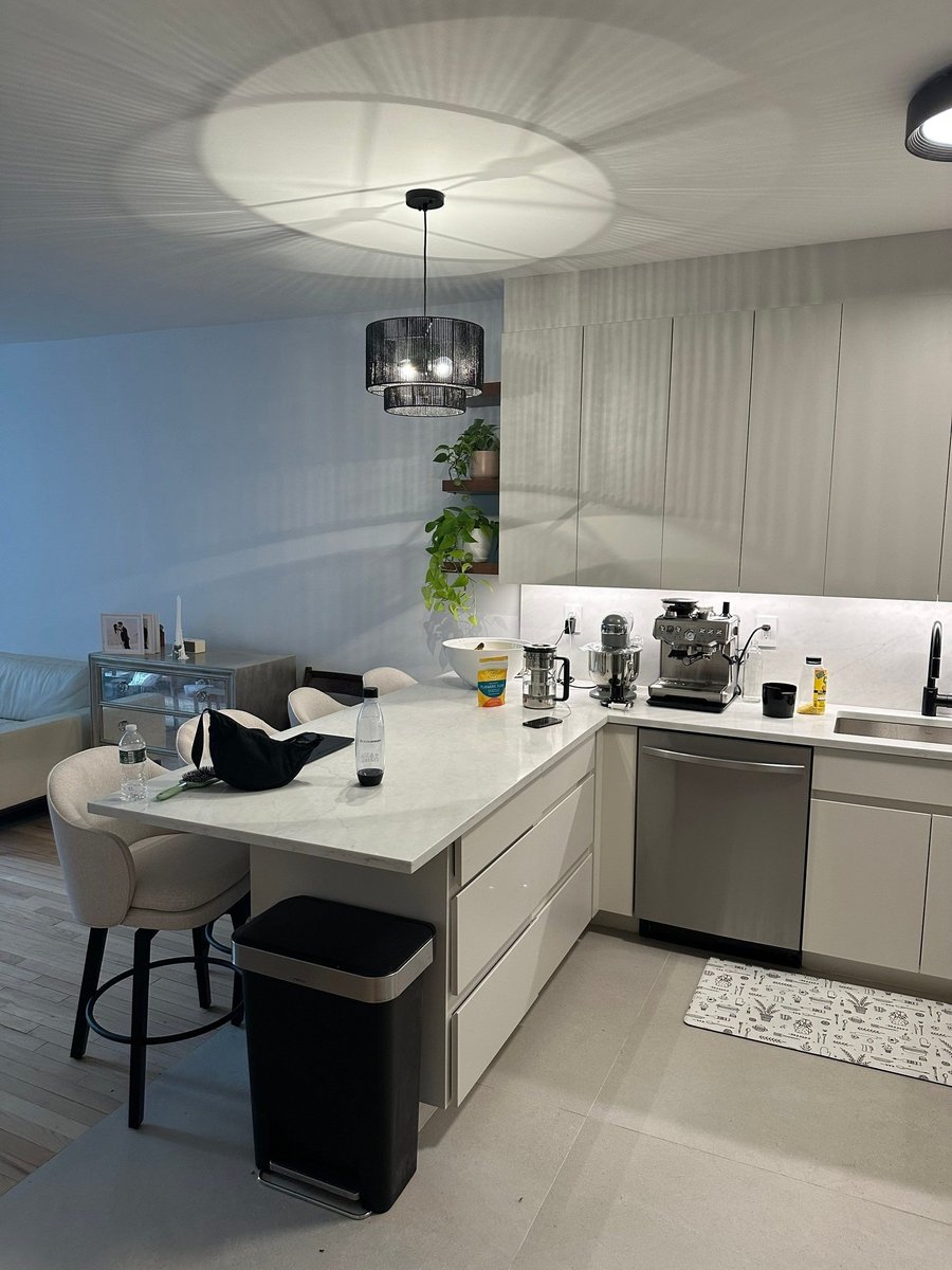 apartment renovation kitchen island with white quartz countertop bar stools black pendant light and gray cabinetry in manhattan valley ny by modo renovations