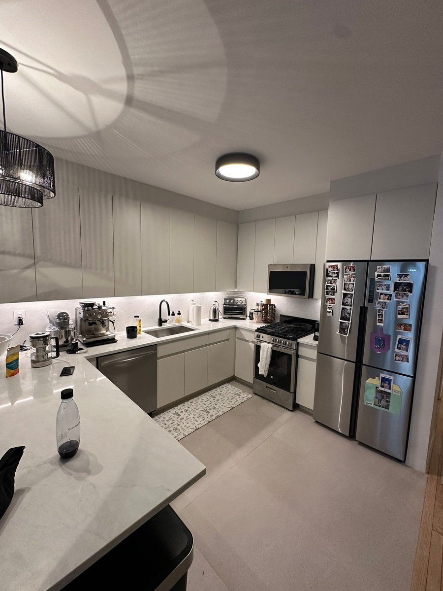 apartment renovation kitchen with gray flat panel cabinets white quartz counters stainless gas range microwave and french door refrigerator in manhattan valley ny by modo renovations