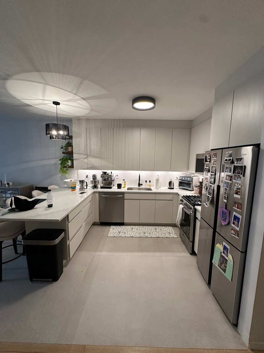 apartment renovation open plan kitchen with gray flat panel cabinets white quartz island stainless appliances and pendant lighting in manhattan valley ny by modo renovations