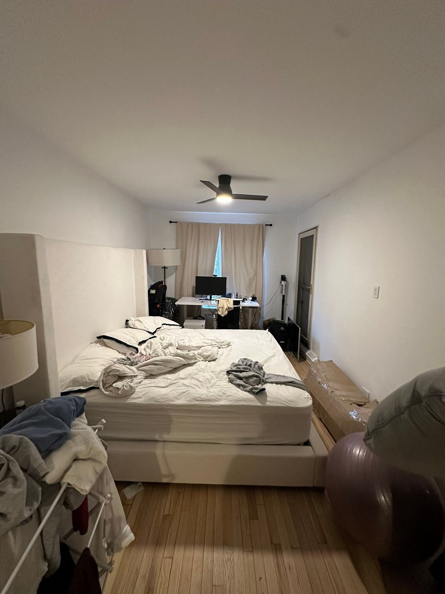 apartment renovation primary bedroom with hardwood floors upholstered bed frame ceiling fan and neutral curtains in manhattan valley ny by modo renovations
